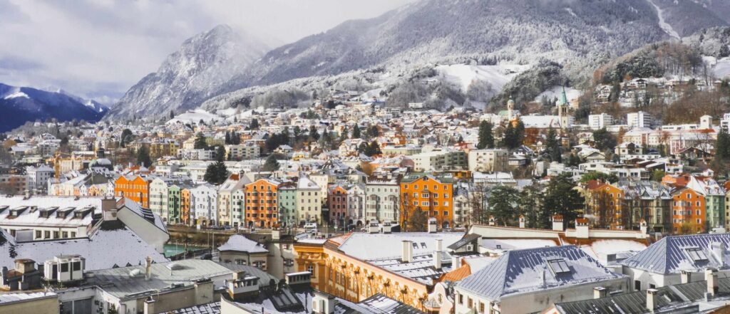 Uitzicht over de gekleurde huizen van Innsbruck in de sneeuw, met de bergen erachter