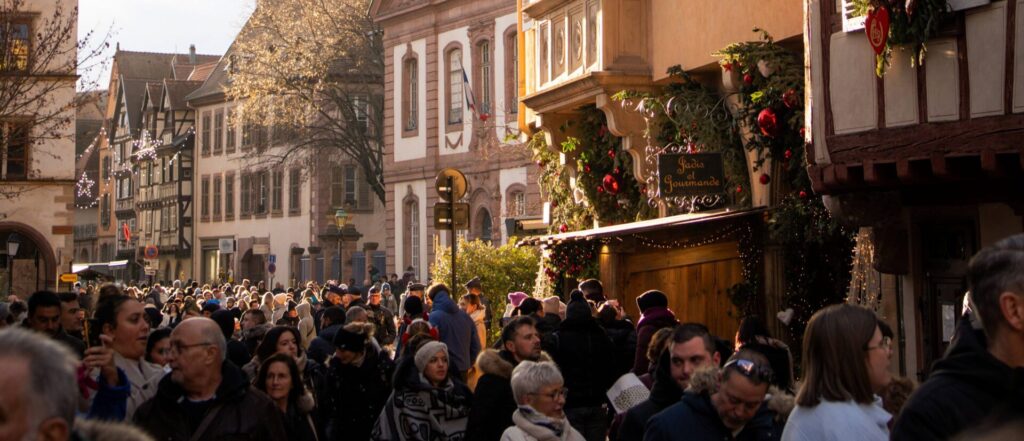Drukke straat in de oude stad van Colmar met kerstversiering en bezoekers in december